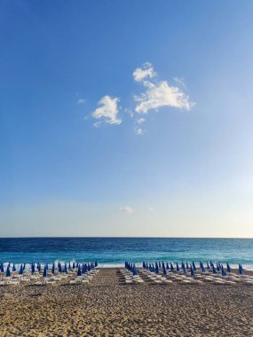 Yazın deniz sahilinde güverte sandalyeleri ve şemsiyeler.