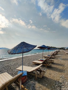 Yazın deniz sahilinde güverte sandalyeleri ve şemsiyeler.