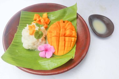 Mango pilavı yapışkan pirinç, mango ve hindistan cevizi sütünden yapılan Tayland tatlısıdır. beyaz arkaplanda izole