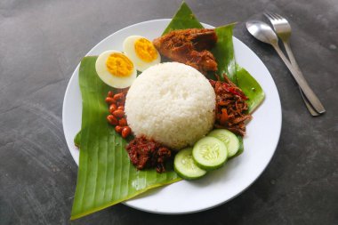 Nasi lemak, geleneksel Malay usulü haşlanmış yumurta, fasulye, ançüez, acı sos, salatalık. Muz yaprağında servis edilen yemekten.