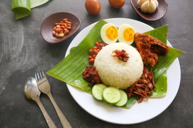 Nasi lemak, geleneksel Malay usulü haşlanmış yumurta, fasulye, ançüez, acı sos, salatalık. Muz yaprağında servis edilen yemekten.