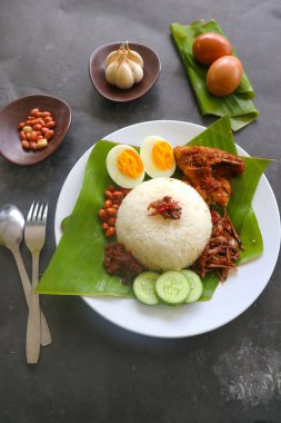 Nasi lemak, geleneksel Malay usulü haşlanmış yumurta, fasulye, ançüez, acı sos, salatalık. Muz yaprağında servis edilen yemekten.