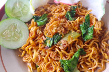 mie tek tek or fried noodle made with egg noodles with chicken, cabbage, mustard greens, meatballs, scrambled eggs. indonesian food