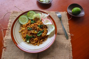 mie tek tek or fried noodle made with egg noodles with chicken, cabbage, mustard greens, meatballs, scrambled eggs. indonesian food