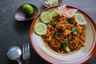 mie tek tek or fried noodle made with egg noodles with chicken, cabbage, mustard greens, meatballs, scrambled eggs. indonesian food