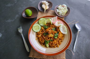 mie tek tek or fried noodle made with egg noodles with chicken, cabbage, mustard greens, meatballs, scrambled eggs. indonesian food