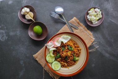 mie tek tek or fried noodle made with egg noodles with chicken, cabbage, mustard greens, meatballs, scrambled eggs. indonesian food