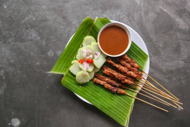 Tavuklu satay ya da satay tavuklu lontong, pirinç keki ve fıstık sosuyla servis edilir. Muz iznine ayrılmış.