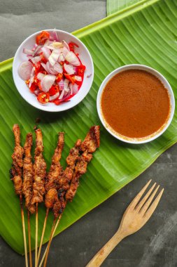 Tavuklu satay ya da satay tavuklu lontong, pirinç keki ve fıstık sosuyla servis edilir. Muz iznine ayrılmış.