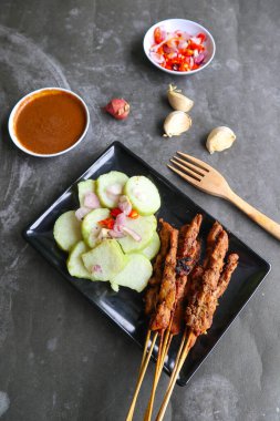 Tavuk satay ya da tavuk satay Lontong, pirinç keki ve fıstık sosuyla servis edilir..