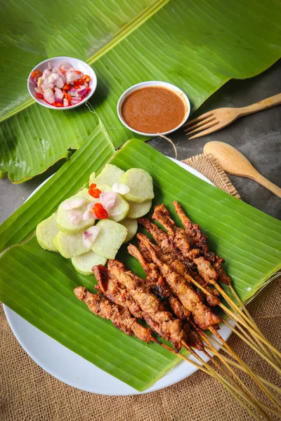 stock image chicken satay or chicken satay served with lontong, rice cake and peanut sauce. served on banana leave