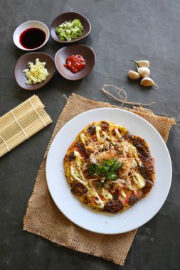 Okonomiyaki, geleneksel Japon pizzası, Okonomiyaki 'den Japon fırında pizza. Un, su veya dashi ile sulandırılmış, artı lahana, tavuk yumurtası, deniz ürünleri ve bir teppan 'da kızartılmış.
