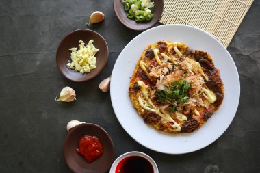 Okonomiyaki, geleneksel Japon pizzası, Okonomiyaki 'den Japon fırında pizza. Un, su veya dashi ile sulandırılmış, artı lahana, tavuk yumurtası, deniz ürünleri ve bir teppan 'da kızartılmış.