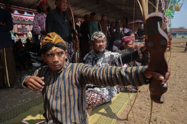 Klaten, Endonezya, 15 Ağustos 2023 Cava geleneklerine göre giyinmiş erkek ve kadın katılımcılar, geleneksel Cava ok ticaretinde hedef doğruluğu konusunda yoğunlaşmak için gözlerini kısarak selam verdiler.