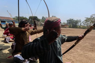 Klaten, Endonezya, 15 Ağustos 2023 Cava geleneklerine göre giyinmiş erkek ve kadın katılımcılar, geleneksel Cava ok ticaretinde hedef doğruluğu konusunda yoğunlaşmak için gözlerini kısarak selam verdiler.
