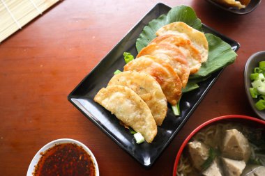 Kızarmış wonton. Acı biberli wonton. Masada hardallı, yeşil soğanlı karides ya da et köftesi çorbası.