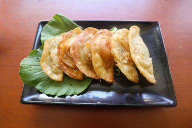 Kızarmış wonton. Acı biberli wonton. Masada hardallı, yeşil soğanlı karides ya da et köftesi çorbası.