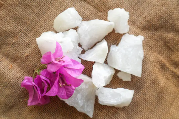 alum, Crystal clear alum stones or Potassium alum on plate, decorated with flowers. Useful for beauty and spa treatment. Use to treat body odor under the armpits as deodorant and make water clear.