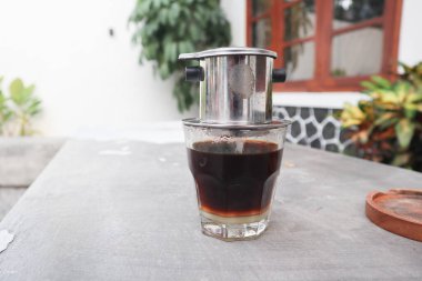 Vietnam damlası, cam bardaklarda yoğunlaştırılmış süt ve geleneksel metal kahve makinesi phin ile Vietnam kahvesi. Geleneksel Vietnam kahvesi yapma yöntemi. Açık havada servis edilir.