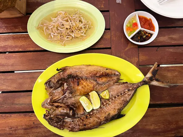 stock image Grilled tuna or Grilled Komo tuna or grilled cue fish, served with chili sauce and soy sauce on a plate on a wooden table, ikan bakar makasar