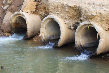Kanalizasyon borusu. Su, bir sonraki nehre giden bir drenaj borusundan akıyor.