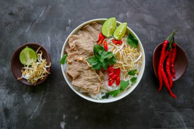 Biftek, pirinç eriştesi, zencefil, limon ve biberli geleneksel Pho Bo çorbası. Kapatın. Siyah arka planda servis edilen Vietnam mutfağı