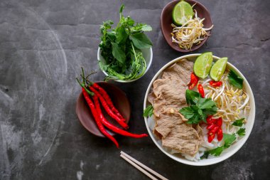 Biftek, pirinç eriştesi, zencefil, limon ve biberli geleneksel Pho Bo çorbası. Kapatın. Siyah arka planda servis edilen Vietnam mutfağı