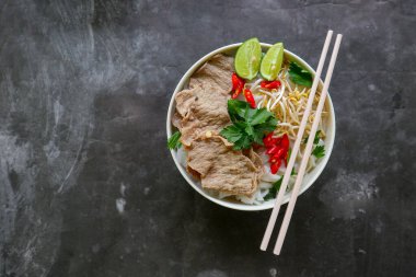 Biftek, pirinç eriştesi, zencefil, limon ve biberli geleneksel Pho Bo çorbası. Kapatın. Siyah arka planda servis edilen Vietnam mutfağı