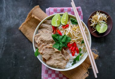 Biftek, pirinç eriştesi, zencefil, limon ve biberli geleneksel Pho Bo çorbası. Kapatın. Siyah arka planda servis edilen Vietnam mutfağı