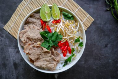 Biftek, pirinç eriştesi, zencefil, limon ve biberli geleneksel Pho Bo çorbası. Kapatın. Siyah arka planda servis edilen Vietnam mutfağı