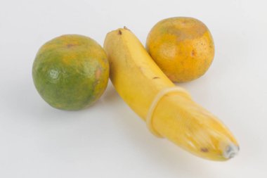 A banana is on the left side of a picture of two oranges with condom. The bananas A metaphor of sex, sexuality, penis. photo with blur effect