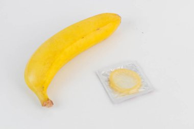 Beyaz arka planda muz ve prezervatif yan yana yerleştirilir.