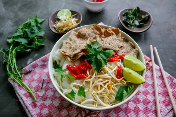 Biftek, pirinç eriştesi, zencefil, limon ve biberli geleneksel Pho Bo çorbası. Kapatın. Siyah arka planda servis edilen Vietnam mutfağı