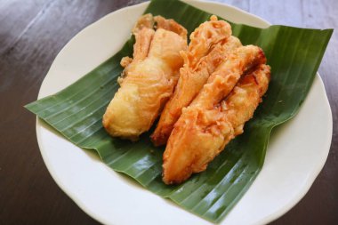 Kızarmış muz ya da muz yapraklı bir tabakta servis edilen pisang goreng. Tabak ahşap bir masanın üzerinde.