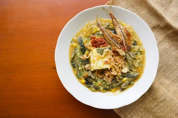 stock image Manado Porridge or Tinutuan Porridge is tradisional porridge. Manadonese rice porridge, mixed with pumpkin, corn, vegetables. Served with tofu salted fish and chili sauce or sambal