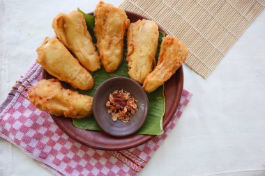 Kızarmış muz ya da muz yapraklı bir tabakta servis edilen pisang goreng. Tabak ahşap bir masanın üzerinde.