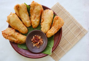 Kızarmış muz ya da muz yapraklı bir tabakta servis edilen pisang goreng. Tabak ahşap bir masanın üzerinde.