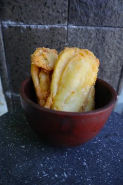 Kızarmış muz ya da muz yapraklı bir tabakta servis edilen pisang goreng. Tabak ahşap bir masanın üzerinde.