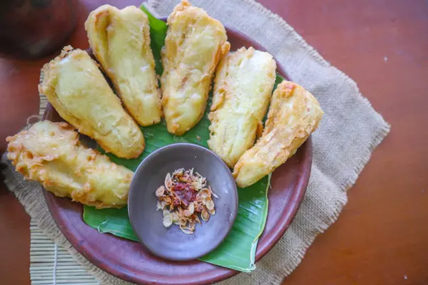 stock image fried bananas or pisang goreng served on a plate with banana leaf. The plate is on a wooden table