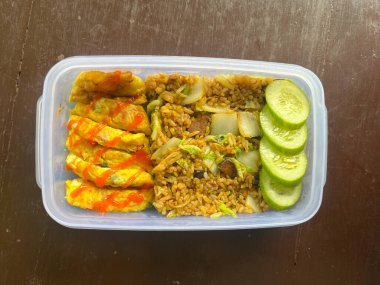 Kızarmış pirinç, omlet, salatalık dilimleri, Asyalılar için öğle yemeği.