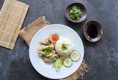 Salatalık dilimi, et suyu ve sos ile servis edilen tavuk çorbasıyla pişirilmiş tavuk pirinci veya nasi hainan veya pilav.