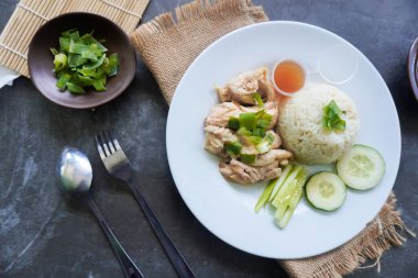 Salatalık dilimi, et suyu ve sos ile servis edilen tavuk çorbasıyla pişirilmiş tavuk pirinci veya nasi hainan veya pilav.