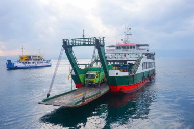 Denizi geçen feribot, kamyonlar, arabalar ve yolcular, araçlar taşıyan bir teknenin güvertesi. Bali Boğazı 'nda yoğun deniz trafiği