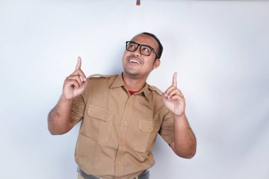 Asyalı bir memur ya da devlet memuru kahverengi üniformalı beyaz arka plandaki fotokopi alanını işaret ediyor. Endonezya PNS, ASN