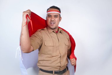 Asyalı devlet memurları veya devlet memurları kahverengi üniformalı, kırmızı ve beyaz bantlı mutlu ve başarılı bir ifade sergileyerek beyaz arka planda bir yumruk kaldırdılar. Endonezya PNS, ASN. Kırmızı ve beyaz bayrak taşıyor