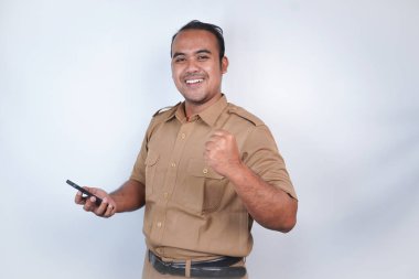 Asyalı bir devlet memuru ya da devlet memuru kahverengi üniformalı bir jest bandıyla telefonunu tutar ve fotokopi makinesini ona doğrultur. Beyaz arka planda. Endonezya PNS, ASN