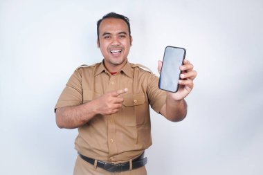 Asyalı devlet memurları veya devlet memurları gülümseyen bir adam kahverengi üniformalı bir jestle telefonunu gösterir. Beyaz arka planda. Endonezya PNS, ASN
