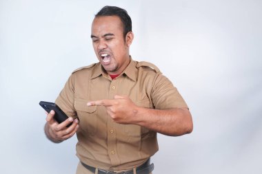 Asyalı bir devlet memuru ya da devlet memuru kahverengi üniformalı bir adama öfkeyle hitap edilir. El telefonunda kızgın. Beyaz arka planda. Endonezya PNS, ASN
