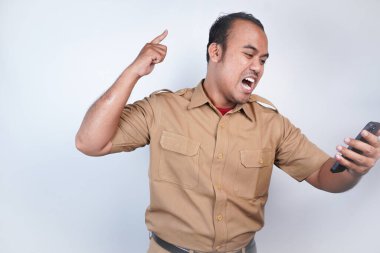 Asyalı bir devlet memuru ya da devlet memuru kahverengi üniformalı bir adama öfkeyle hitap edilir. El telefonunda kızgın. Beyaz arka planda. Endonezya PNS, ASN