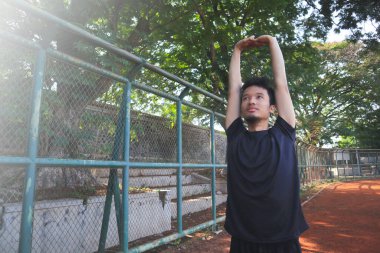 Bir adam çitin önünde kolunu uzatıyor. Kararlılık kavramı ve adam esnekliği üzerinde çalışırken odaklanma.